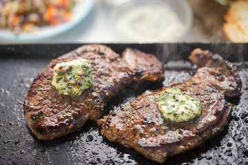 Angus steaks with garlic butter on barbecue with salad and dips. Barbecue party 