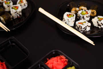 Delicious and healthy vegan rolls lie in a black plate on the table.