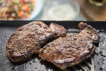Ranch steaks on barbecue with salad, sauce in the soft focus background