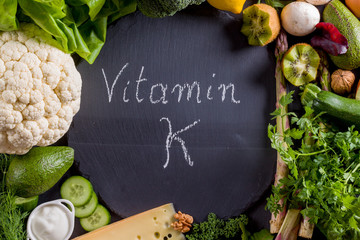 Green vegetables rich in vitamin K on black slate.