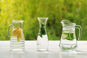 Three variants of fresh homemade lemonade with lemon, cucumber and mint. Lemonade in jugs and...