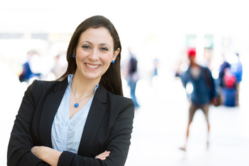 Urban girl standing out from the crowd at a city street. Businesswoman posing confident and smiling