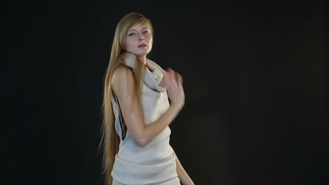 blonde model of European appearance posing in front of camera in studio on black background
