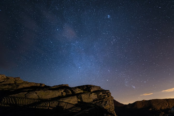 Night on the Alps under starry sky and the majestic rocky cliffs on the Italian Alps, with Orion...