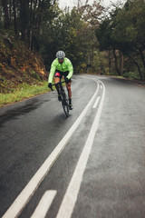 Fototapeta na wymiar Bicycle rider with bike on wet asphalt road