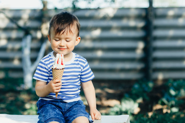 a child in a t-shirt on a bench eating ice cream in the summer, very hot and tasty