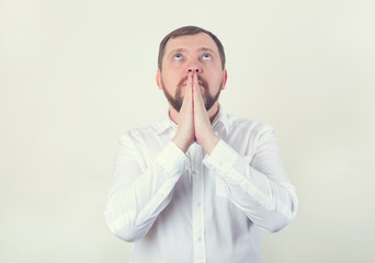 Pray. An adult man with a beard folded his hands in prayer. Religion.