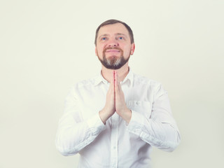 Pray. An adult happy man with a beard in prayer holds his hands in front of him.