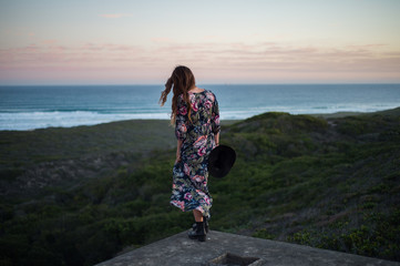 Girl in flower dress overlooks the ocean