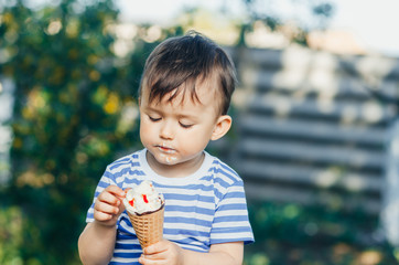 a child in a t-shirt on a bench eating ice cream in the summer, very hot and tasty