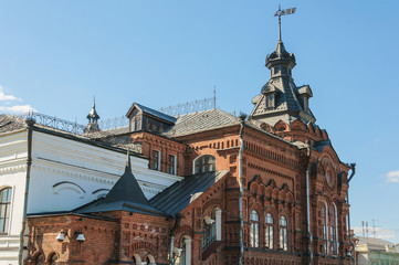 the old building with an arched porch and a tower of red brick. elongated cone. on the background of blue sky