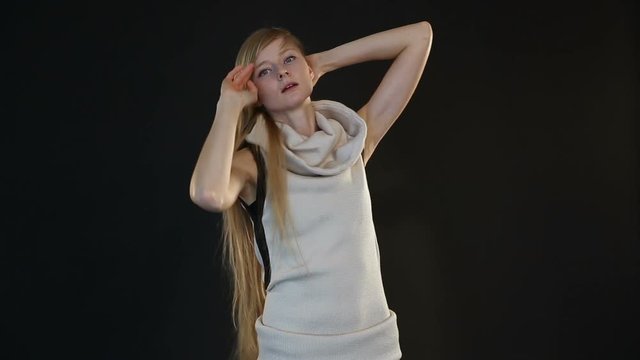 blonde model of European appearance posing in front of camera in studio on black background