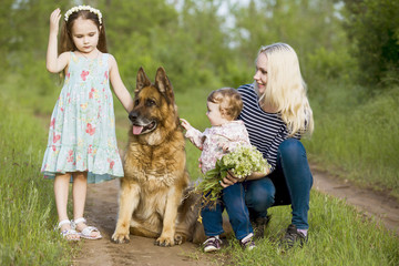 Mother day. Mother with two daughters and a dog, a German Shepherd on a green grass