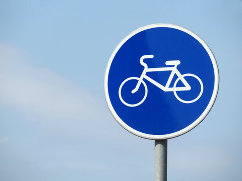 Bicycle road sign isolated on blue sky. White bicycle symbol on the blue circle of sign