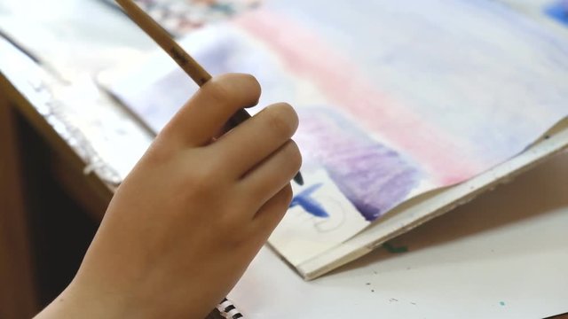 The child learns to paint with watercolors.