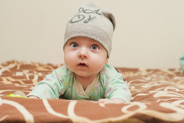 baby 4 months in a cap raised on his hands