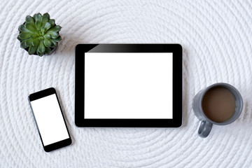 Office table with tablet, computer, coffee cup and flower. View from above with copy space