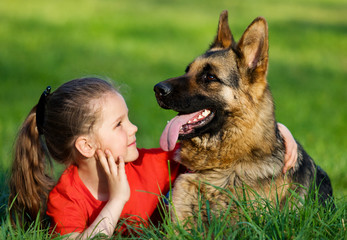 child and dog hugging outdoors