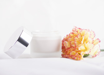 Close-up of flower and pot of cream for skin on white background. Isolated.