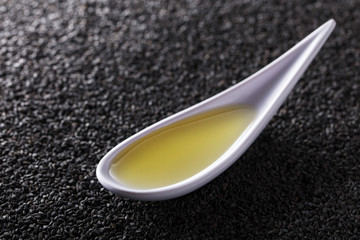 Sesame oil in small bowl on a background of black sesame.