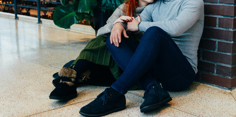 the couple is sitting on the floor in an embrace. embrace. a female hand with a ring, a man's hand with a watch. talking. gray sweaters.
