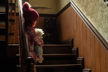 Asian girl hold her doll and cry or scare or sad or feel bad. on the staircase