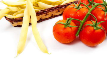 Fresh young pods of beans with beans and bunch of the fresh red tomatoes with water drops on white background..