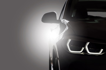 Black modern car Close up detail on one of the LED headlights modern car on gray with light...