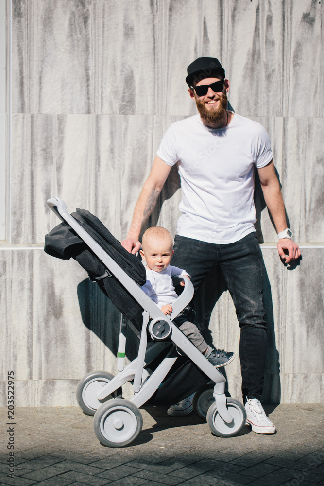 Wall mural Father walking with a stroller and a baby in the city streets