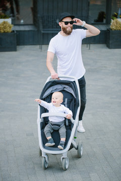Father walking with a stroller and a baby in the city streets
