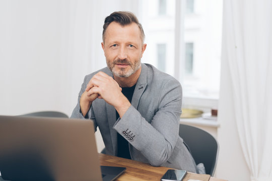 Portrait of mature man sitting in front of laptop