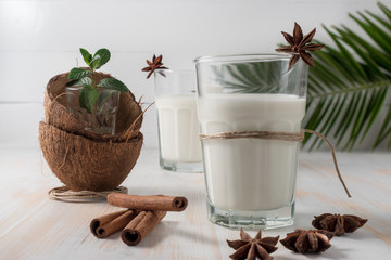 Shell of coconut and coconut milk in glass with cinnamon on wooden table.