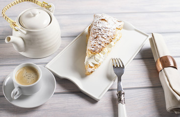 Close-up of delicious breakfast of coffee with sweet puff pastry with cream on wooden table. Horizontal shoot. Food