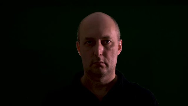 Portrait adult man looking into camera isolated on black background