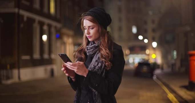 Millennial Caucasian female looking for friend sending text outside in street