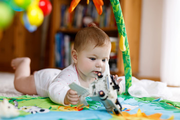 Adorable baby girl playing with educational toys in nursery