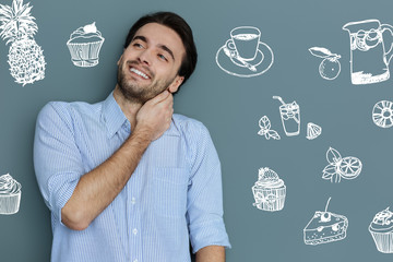 Nice cafe. Cheerful young emotional man smiling while choosing tasty desserts in a new cafe