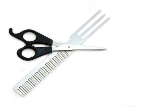 Hairdressing scissors with black handles and a metallic shiny comb on a white background. Close image.