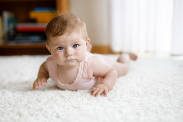 Little funny baby girl lifting body and learning to crawl.