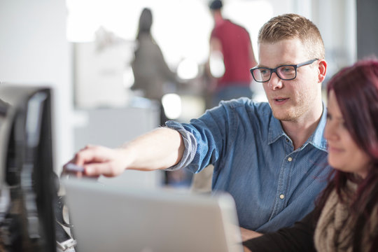 Male and female colleagues working at office computer