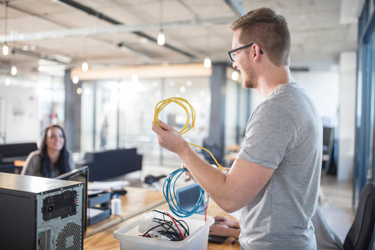 Computer technician repairing cables in office