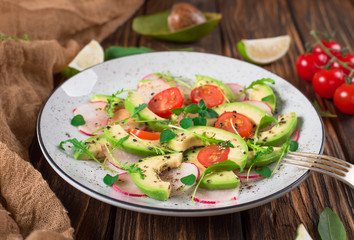 Vegetable salad with avocado, arugula, radish, lime and olive oil. Dietary healthy food. Wooden rustic background. Top view