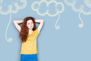 Dreamy mood. Calm young secretary standing with her eyes closed and dreaming about having pleasant weekend