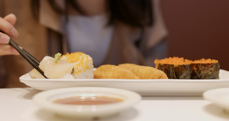 Woman eating sushi in Japanese restaurant