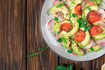 Vegetable salad with avocado, arugula, radish, lime and olive oil. Dietary healthy food. Wooden rustic background. Top view