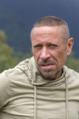 Obraz premium People and lifestyle concept. Happy middle-aged unshaven man outdoor against green nature background, portrait close up