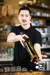 Male barista serving a bottle of wine