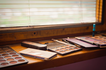 Detail of cosmeticians tools, colors and brushes under the old window