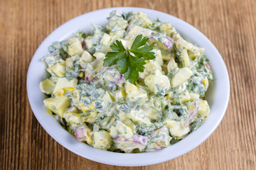 Salad of radish, boiled egg, parsley and sour cream in white bowl - healthy breakfast concept