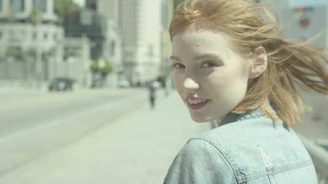 Portrait of young woman with red hair in sunlight slow motion